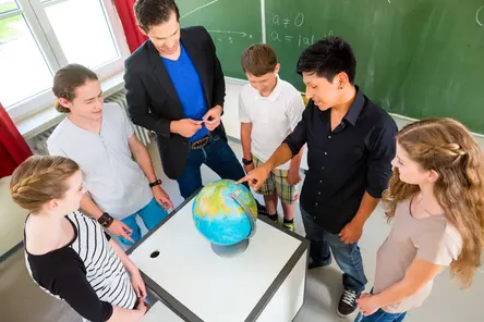 Teacher teaching students geography lessons in school